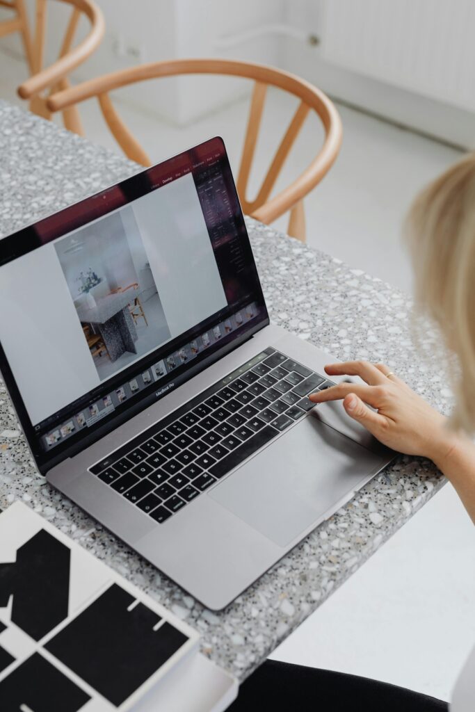 pexels-photo-6032795-6032795 Overhead view of a woman using a laptop on a stylish marble table, displaying a design layout.